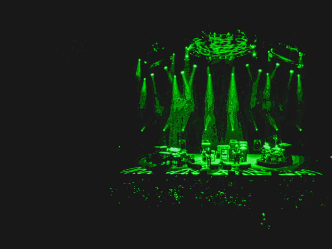 Live Phish concert performance illuminated in green lights, showcasing vibrant stage effects and enthusiastic crowd.